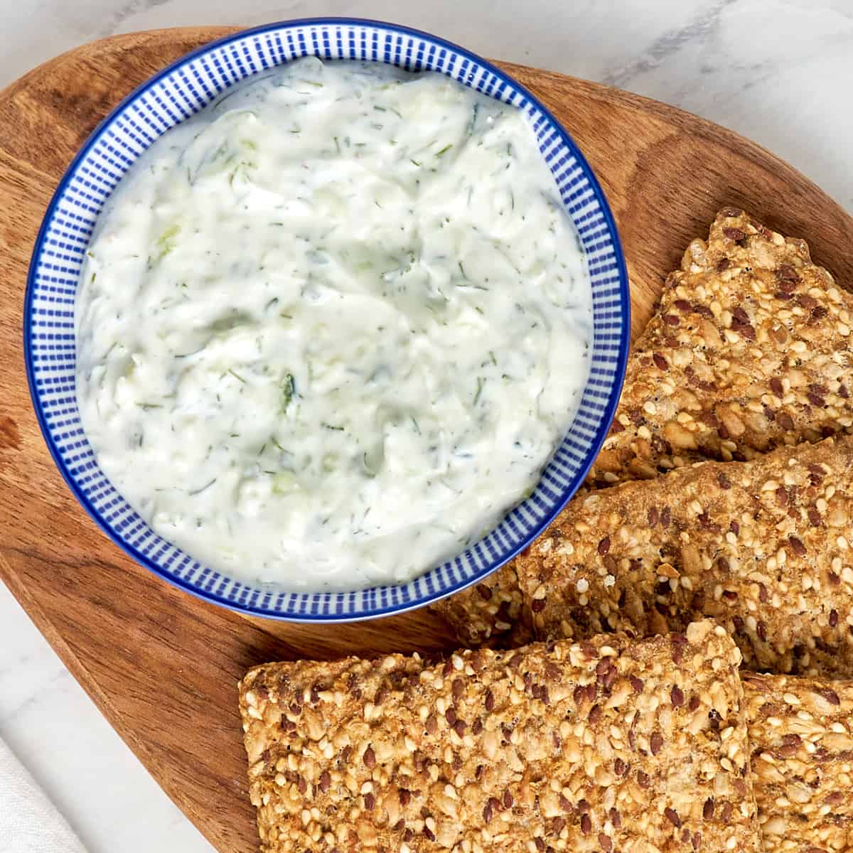 tzatziki sauce in a bowl served with seeded crackers