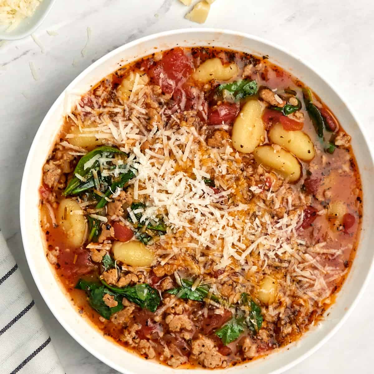 italian sausage gnocchi soup topped with parmesan cheese