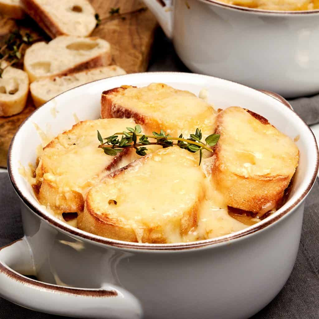 bowl of french onion soup topped with melty cheese and slices of baguette