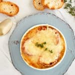 bowl of french onion soup topped with crusty bread and shredded cheese