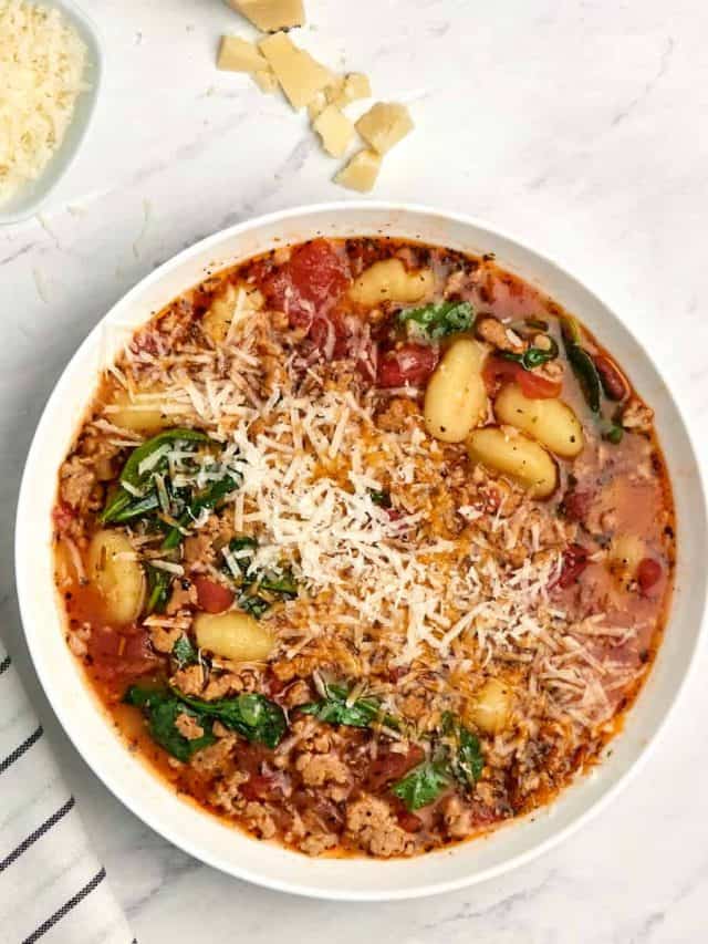 bowl of italian sausage gnocci soup topped with grated parmesan cheese