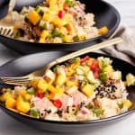 sesame seed crusted seared tuna on top of rice and topped with mango salsa all in a bowl