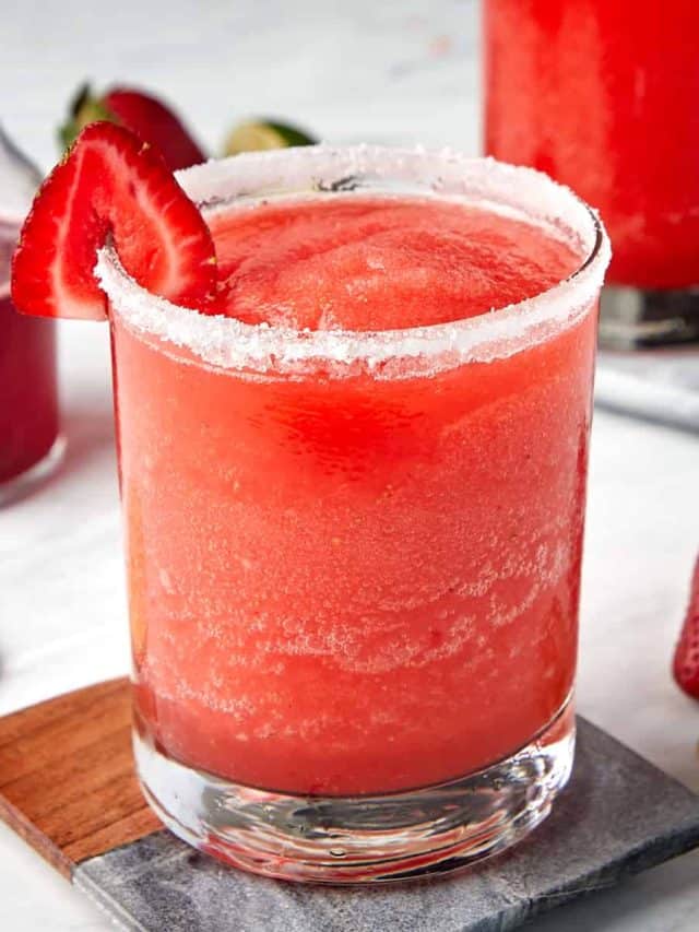frozen strawberry margarita in a glass rimmed with sugar and garnished with a strawberry