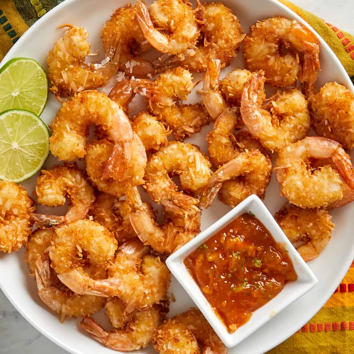 coconut shrimp on a white plate with a side of orange dipping sauce