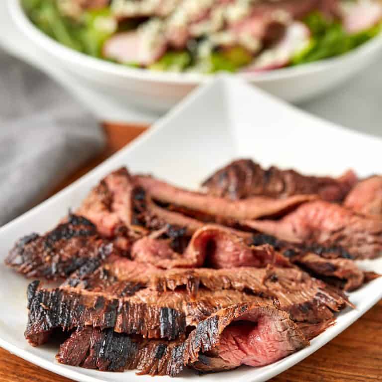 sliced grilled flank steak on a white plate