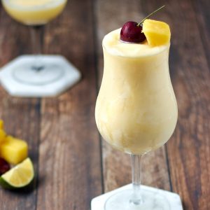 frozen pina colada in glass with pine apple and cherry garnish