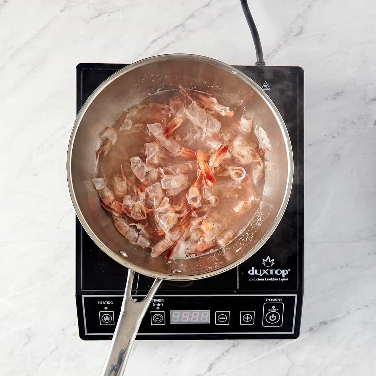 shrimp shells in a pan with water being cooked for stock