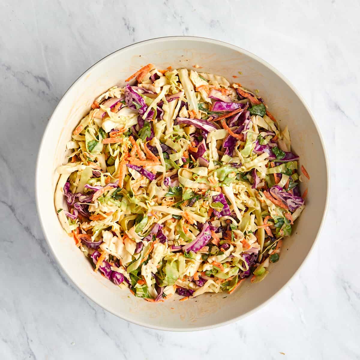 coleslaw in a white bowl after being mixed with dressing