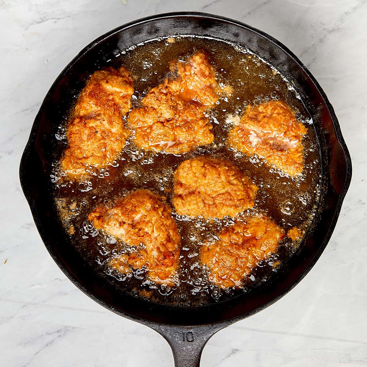 hot chicken frying in a cast iron pan