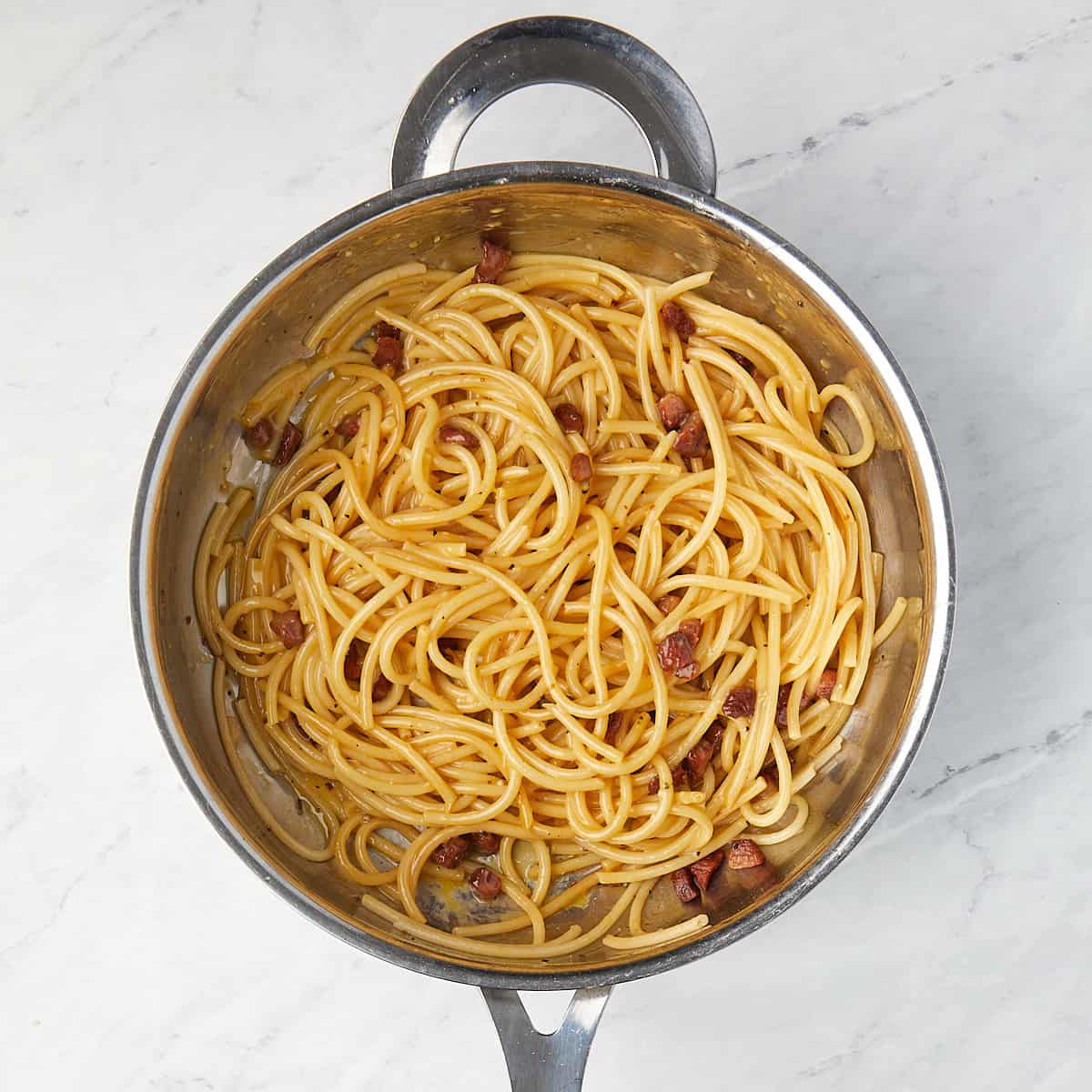 pasta and guanciale in a pan after egg, cheese mixture was stirred in