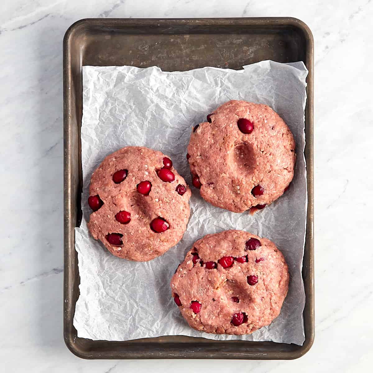 uncooked cranberry turkey burgers on a cookie sheet