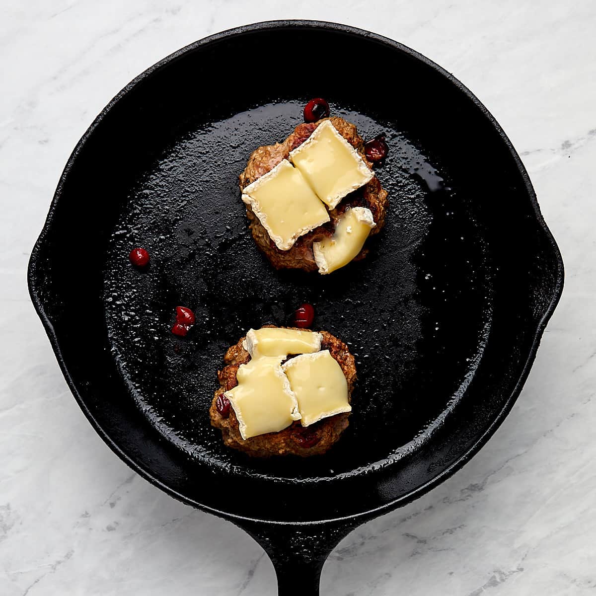 cranberry burgers with brie in a cast-iron pan
