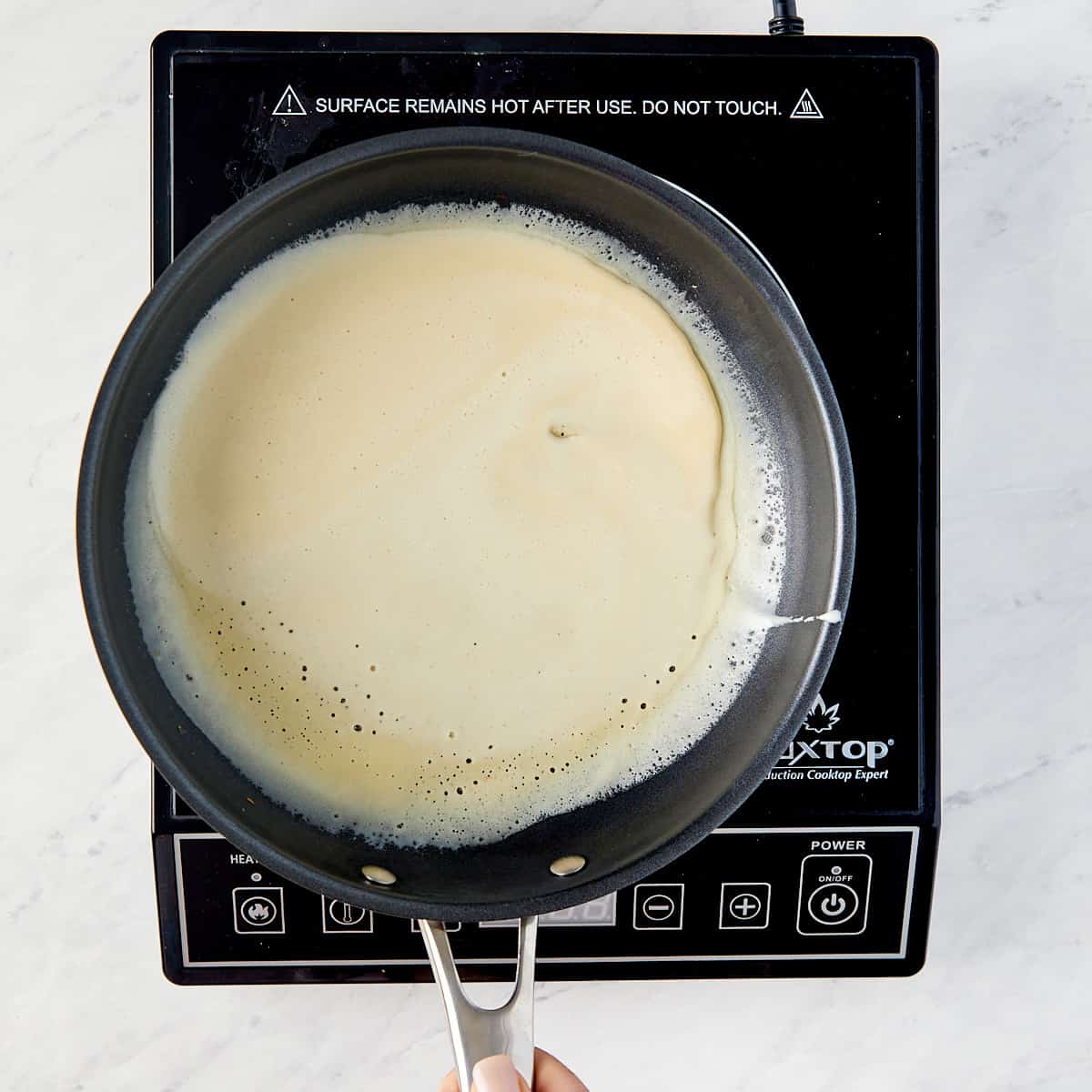 crepe batter being swirled in a pan on a cooktop