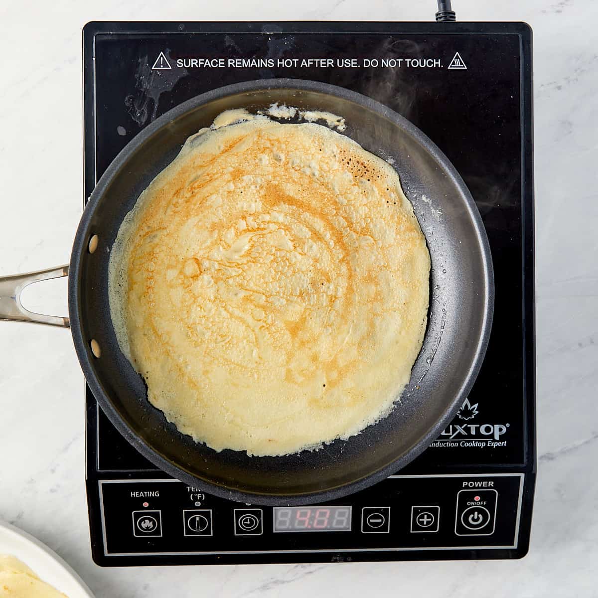 crepe being cooked in a pan on a cooktop
