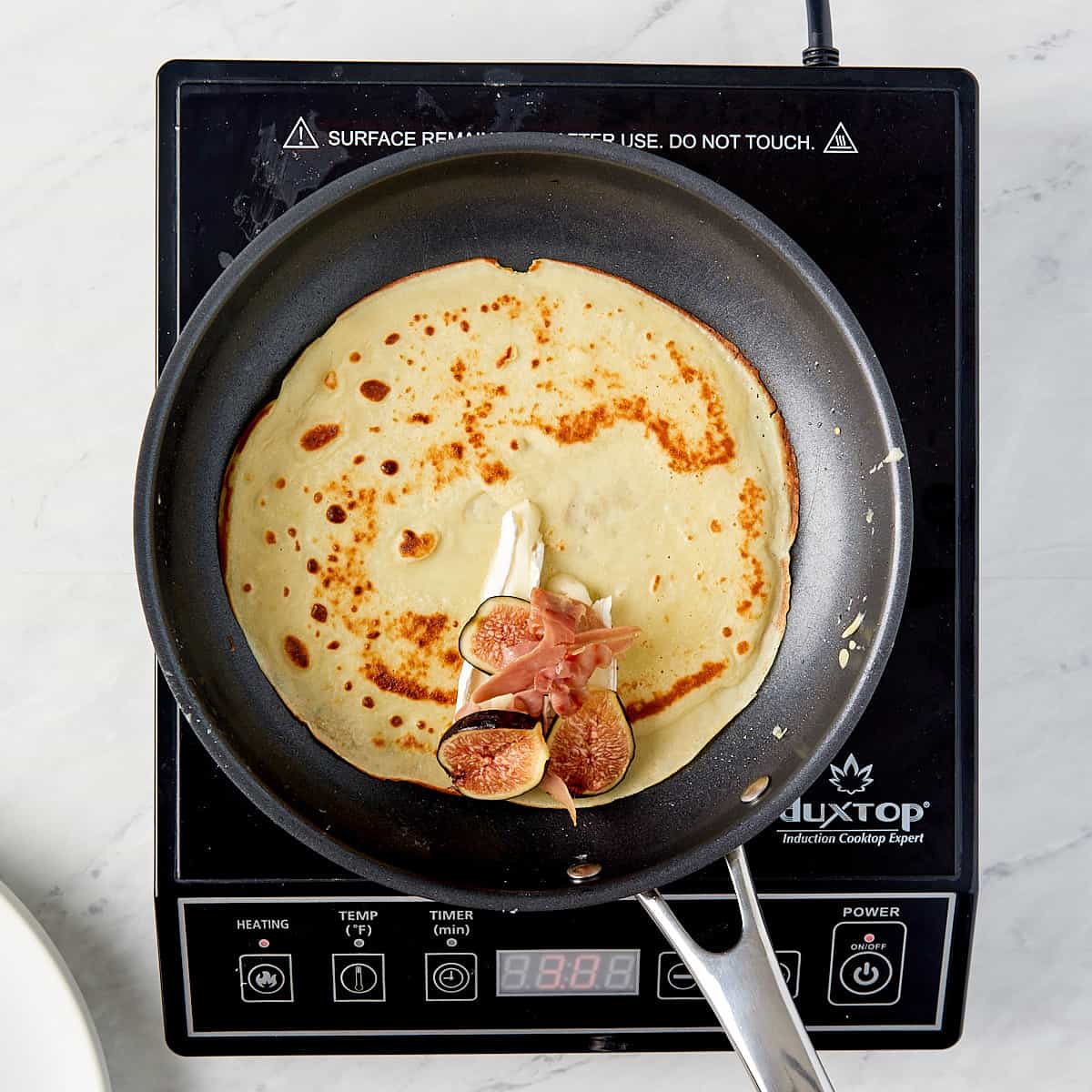 crepe being assembled in a pan on a cooktop