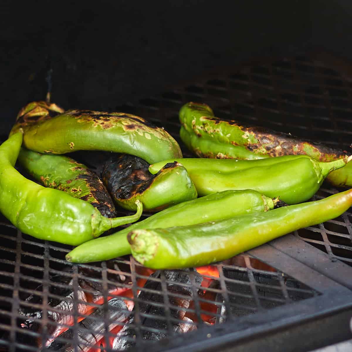 hatch peppers being grilled on a charcoal grill
