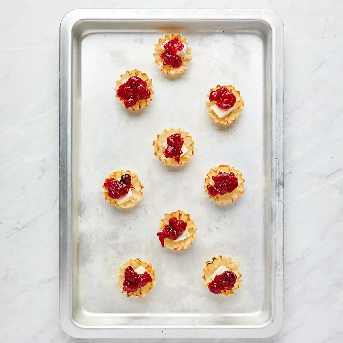 phyllo cups with brie and cranberry sauce on a cookie sheet before baking