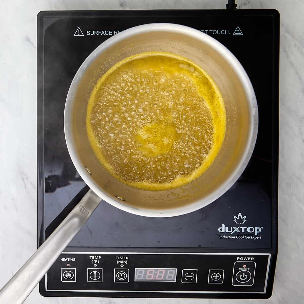 water, sugar, orange juice, and salt being boiled in a saucepan