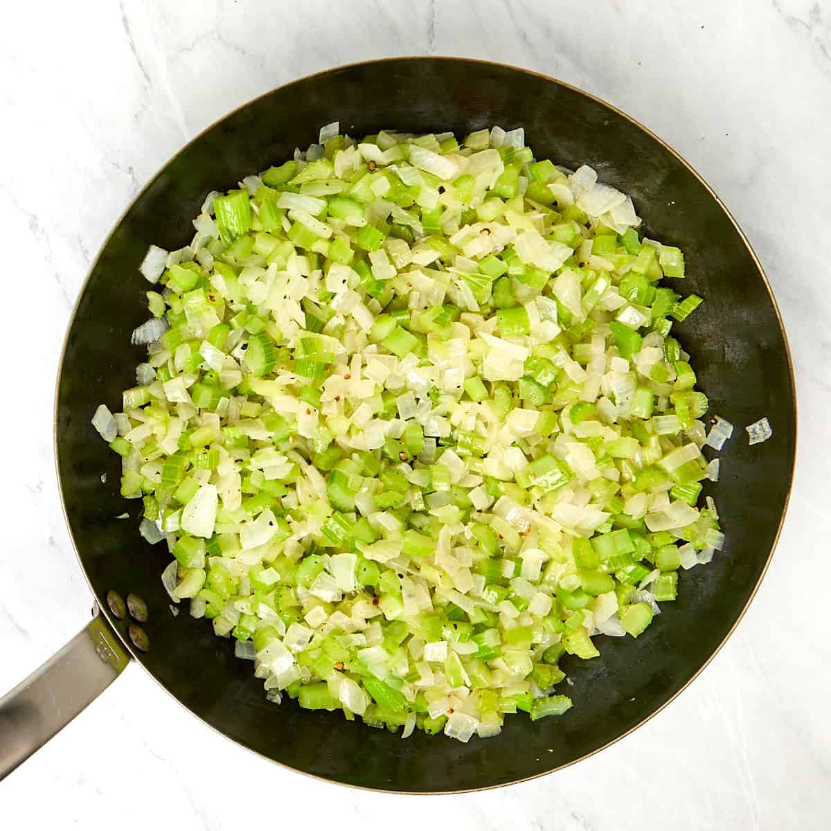 onions and celery being sauteed in a skillet