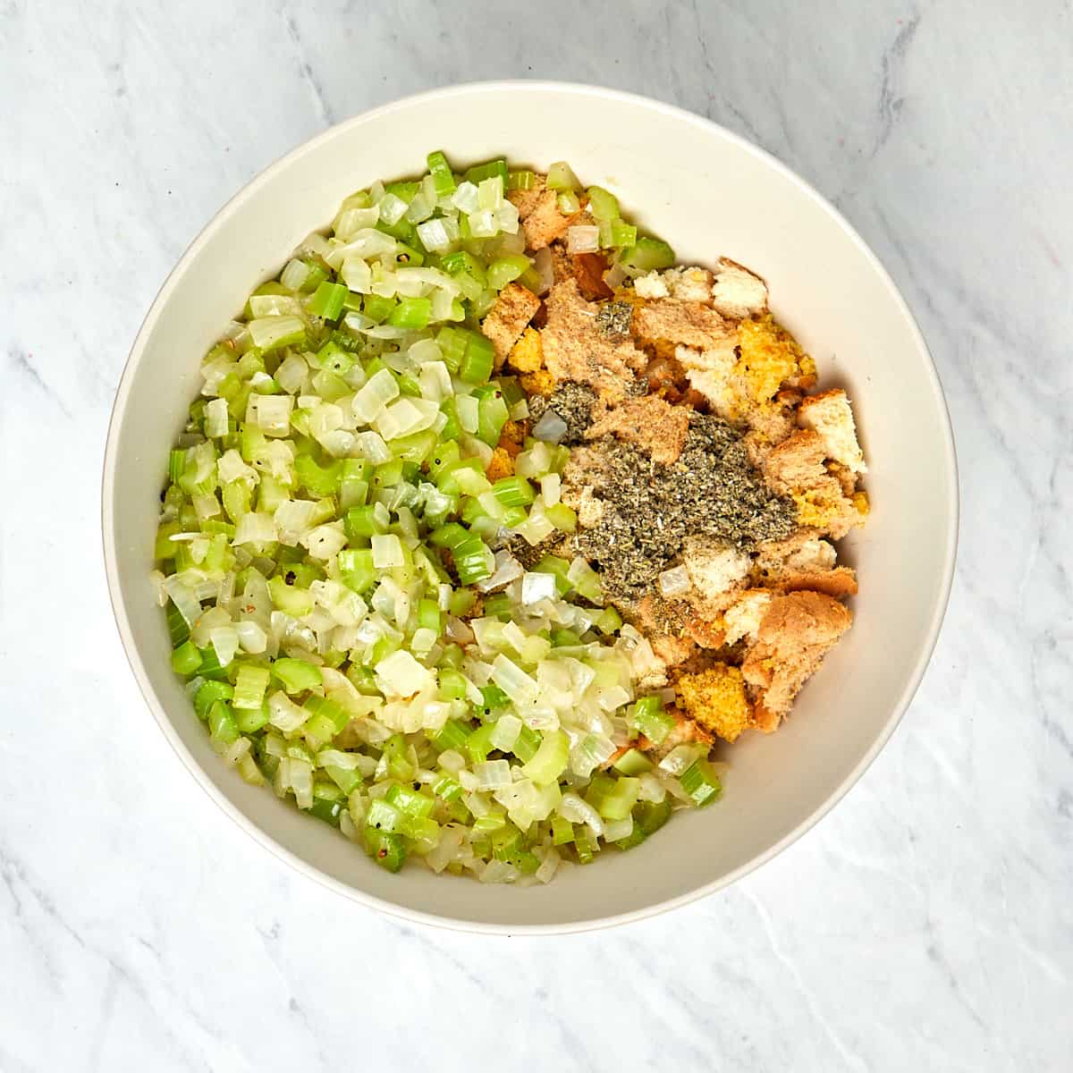 cornbread, bread, spices, and sauteed onion and celery in a bowl