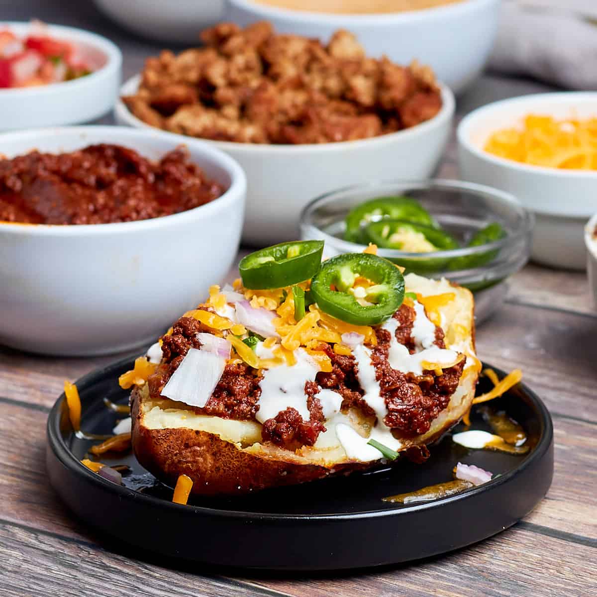 chili cheese baked potato on a black plate