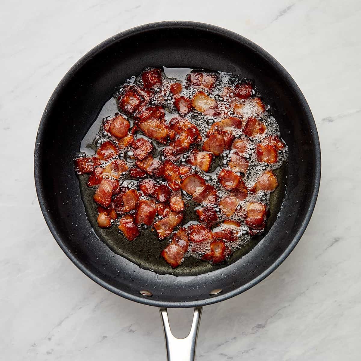 bacon pieces frying in a skillet