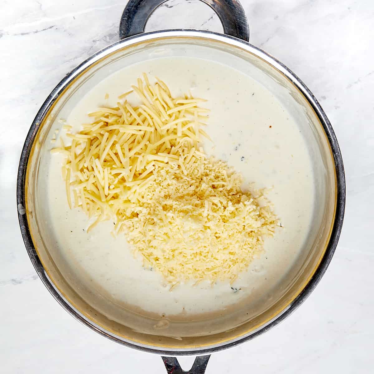 cheese being added to skillet with roux