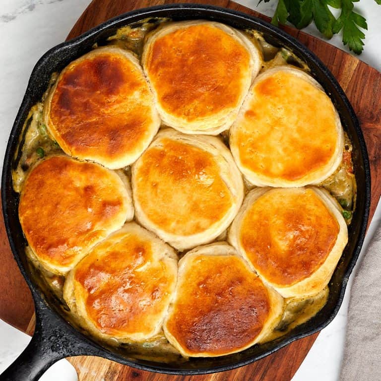 skillet chicken pot pie cooling on a wooden board before serving.