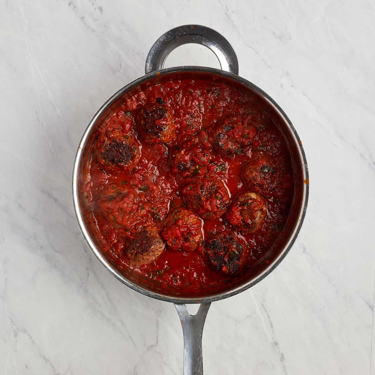 cooked meatballs in the skillet with the tomato sauce.