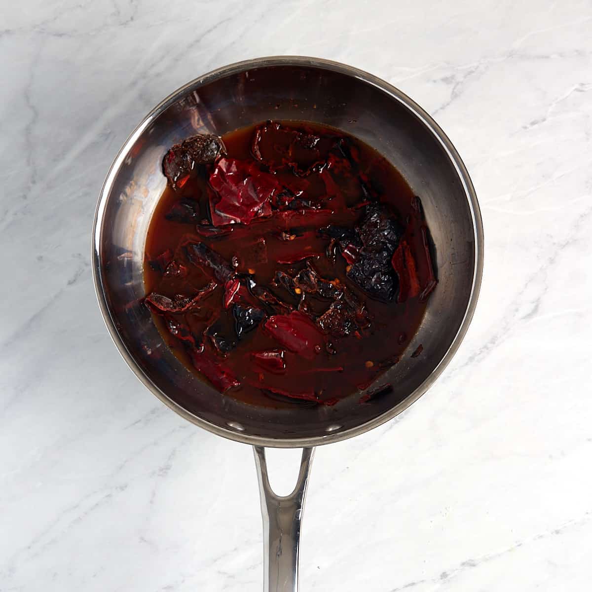 toasted chiles in a saucepan with apple cider vinegar and chicken broth soaking to get soft.
