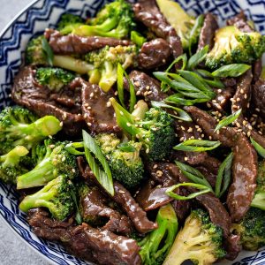 beef and broccoli in a bowl topped with sesame seeds