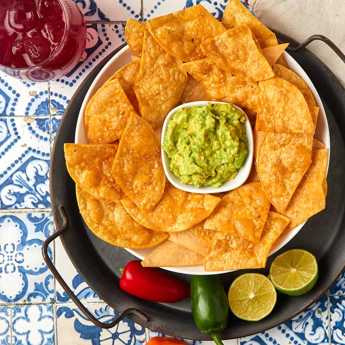 fried tortilla chips in a bowl with a side of guacamole along with a margarita on the rocks.