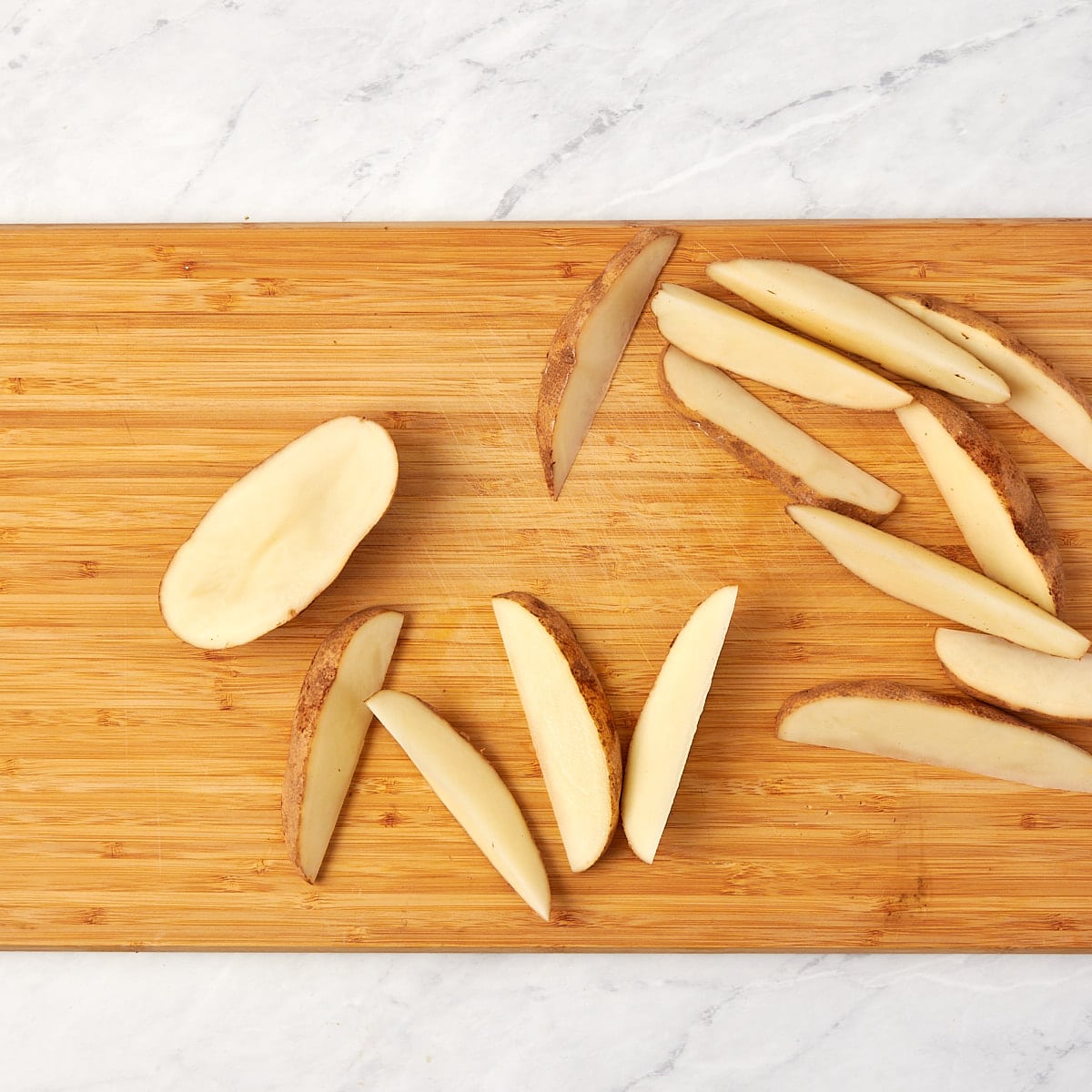 potato being cut in quarters on a cutting board.
