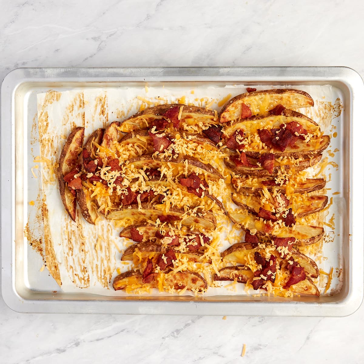 wedges on baking sheet topped with cheese and bacon.