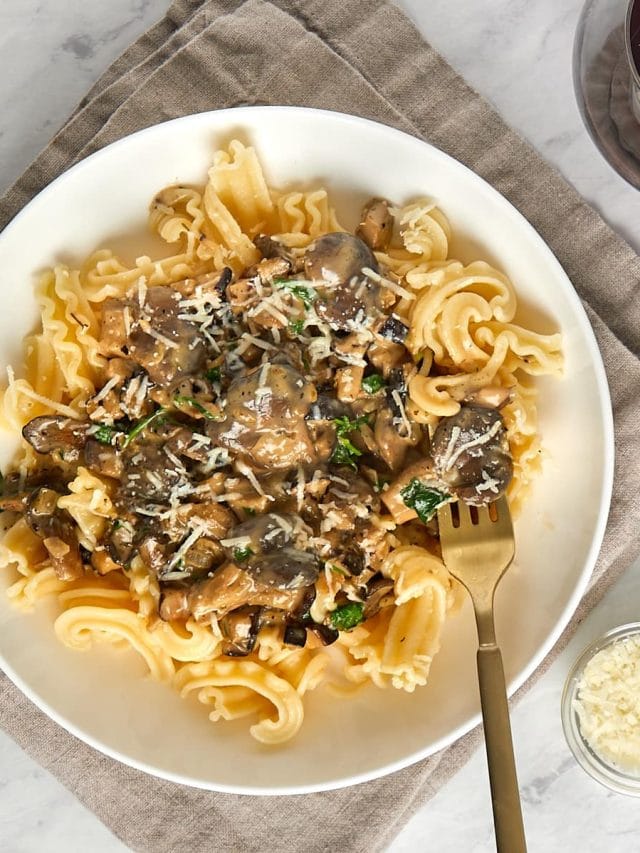 creamy mushroom pasta in a white bowl with a fork.