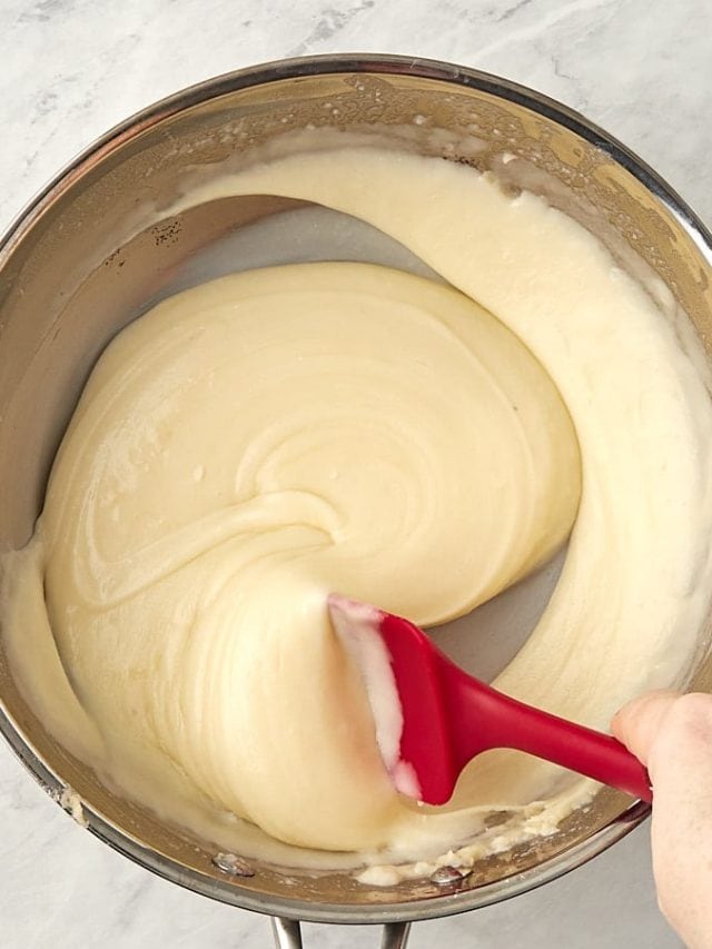 cheese sauce in a skillet being stirred.