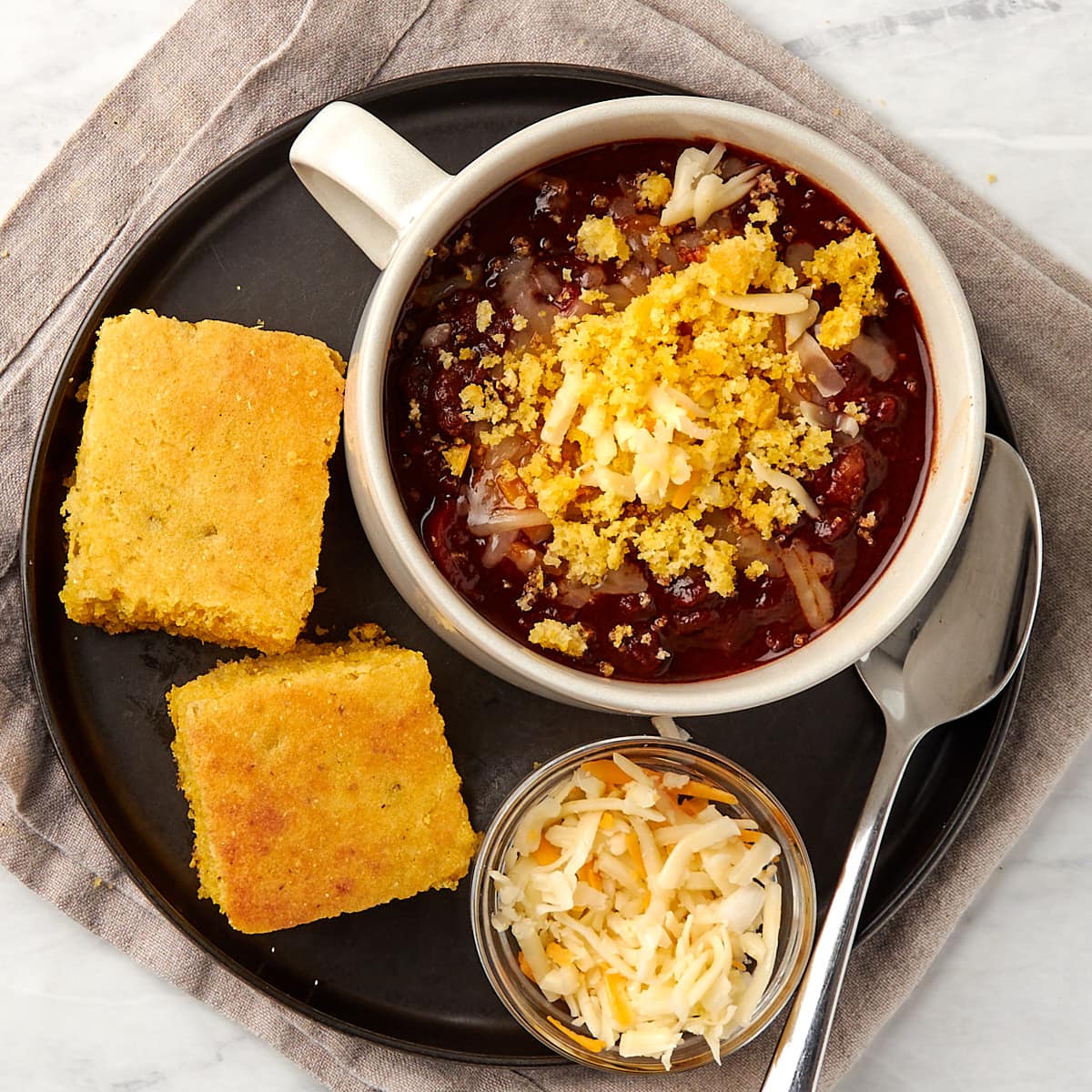 cornbread served with chili. chili topped with cheese and cornbread crumbles.