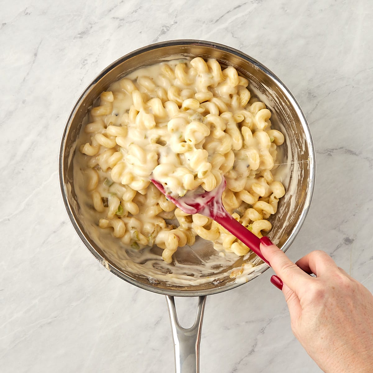 macaroni in a skillet being combined with the cheese sauce.