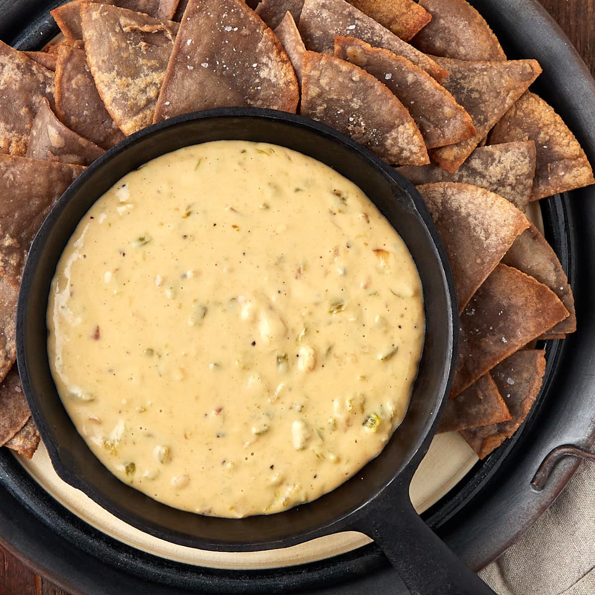 hatch queso in a warm cast iron skillet with a side of tortilla chips.