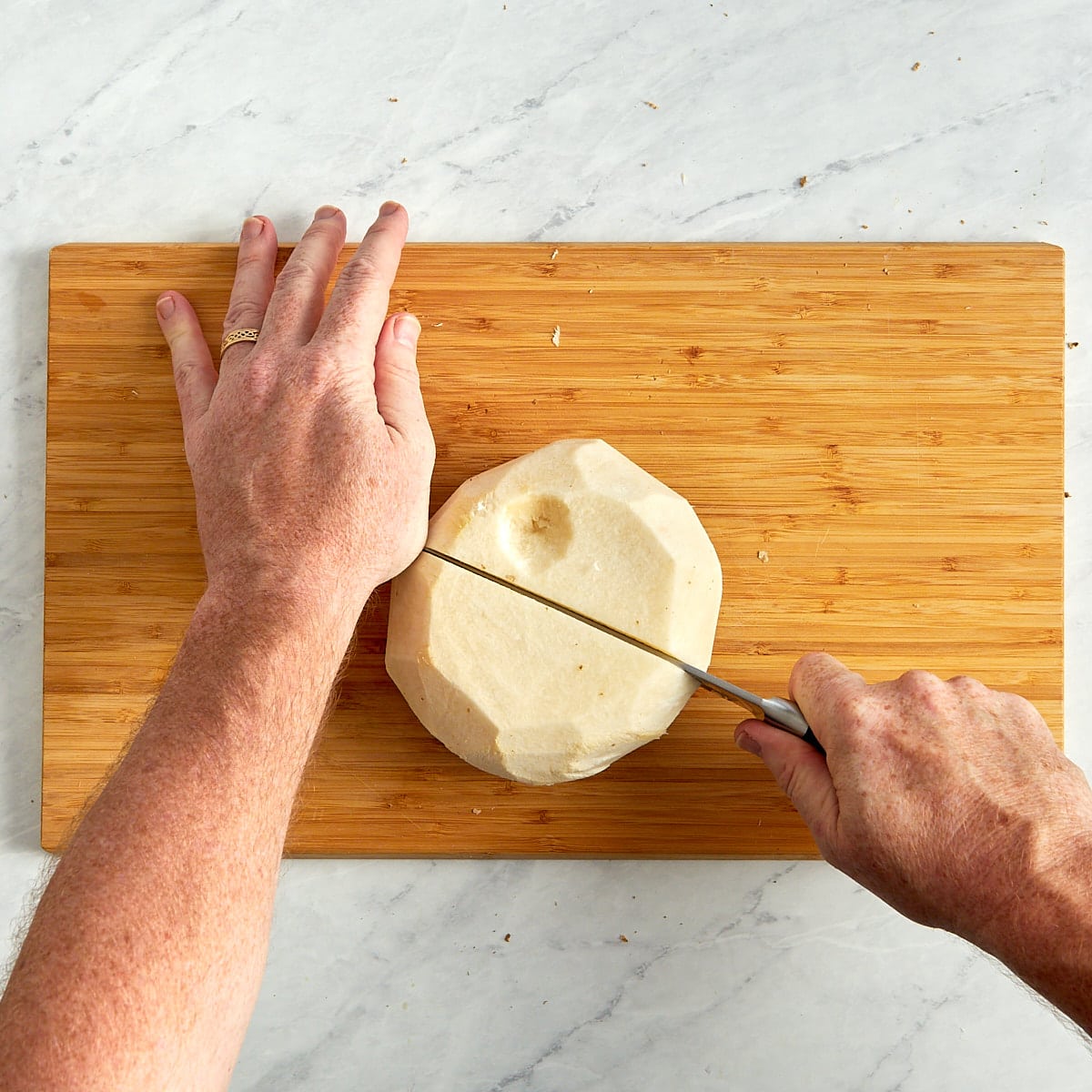 jicama being cut in half on a cutting board.