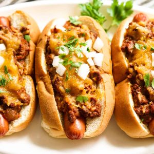 3 chili cheese hot dogs on a plate.