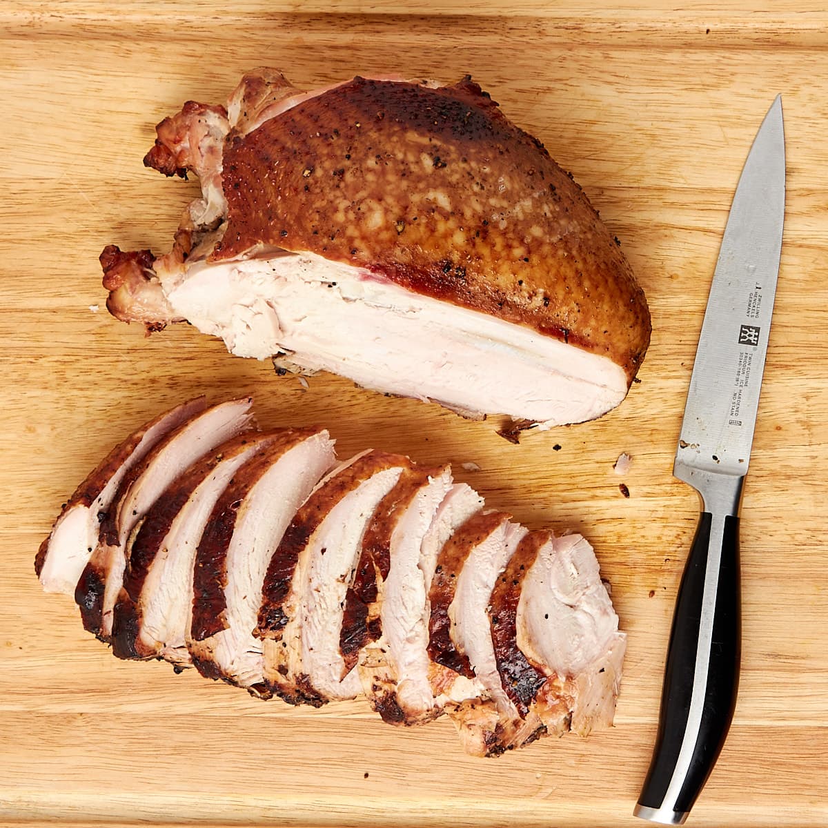 turkey breast on a cutting board with one half of the breast cut off and then sliced.