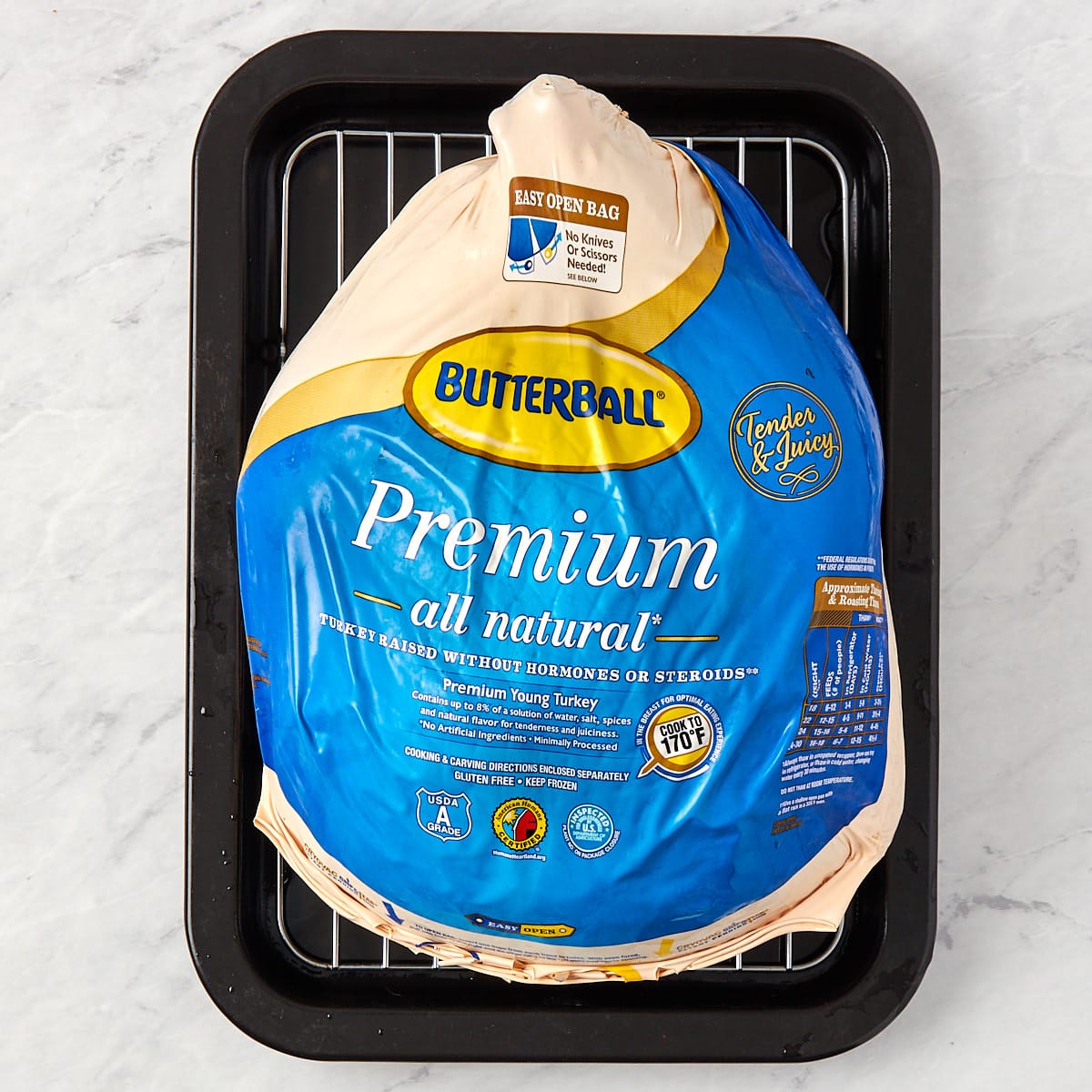frozen turkey in its original package on a tray with a wire rack.