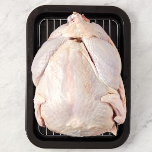 thawed turkey on a wire rack in a pan being.