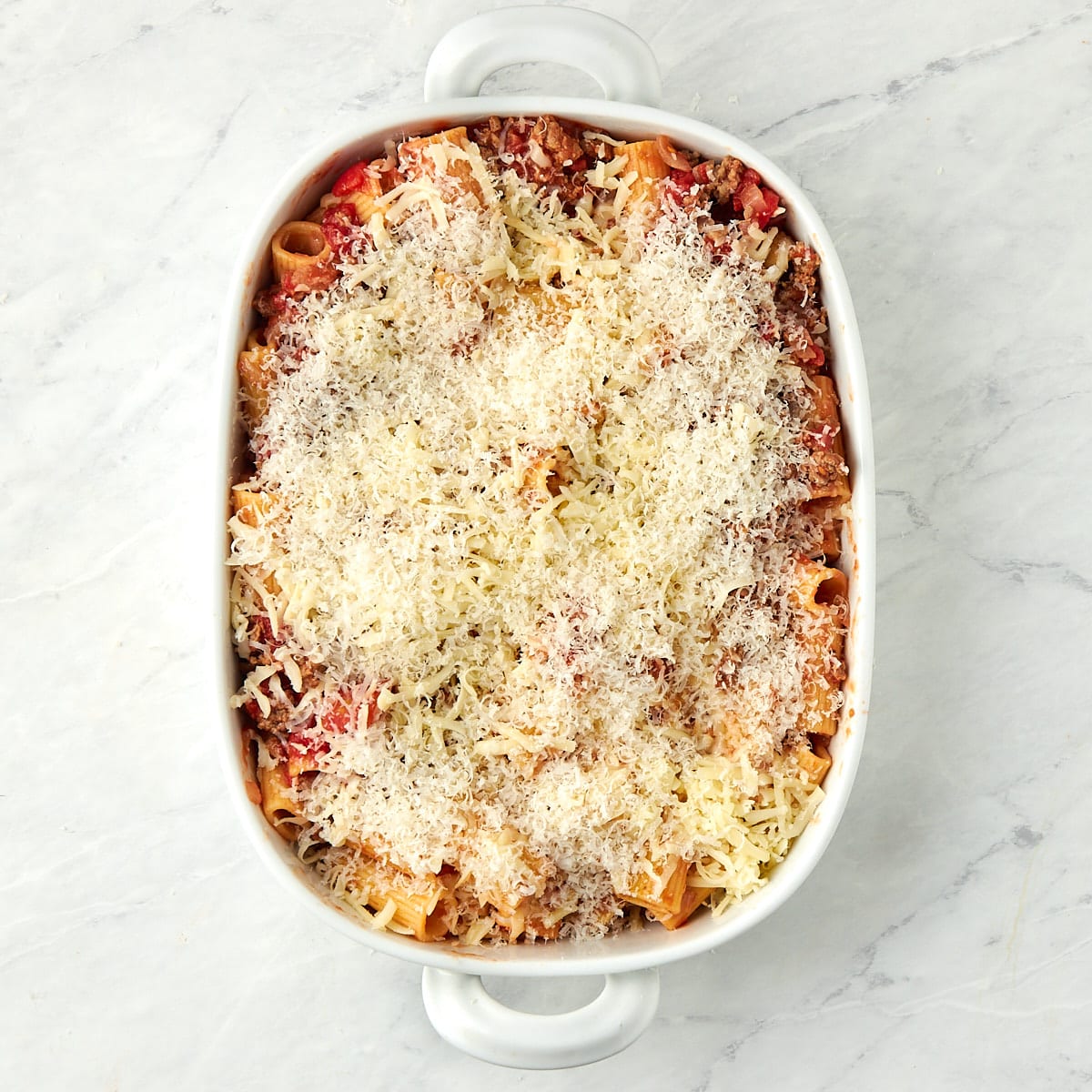 shredded mozzarella and parmigiano reggiano on top of the rigatoni al forno before baking.