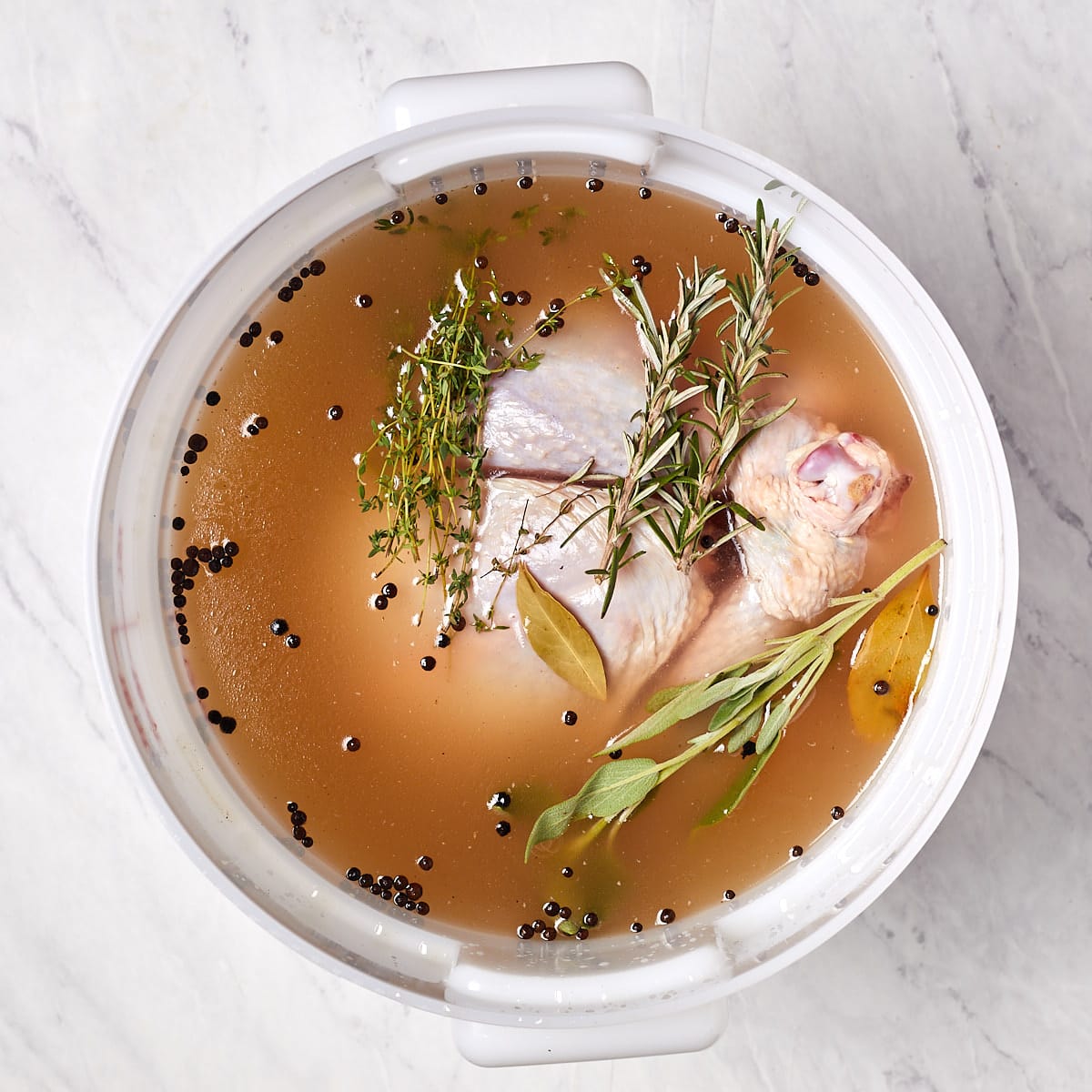 raw turkey in a food grade bucket with the brine and herbs.