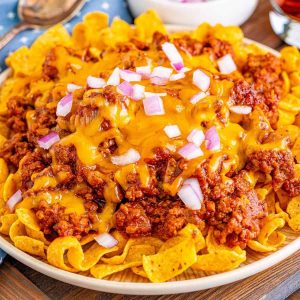 chili cheese frito pie on a plate topped with onions.