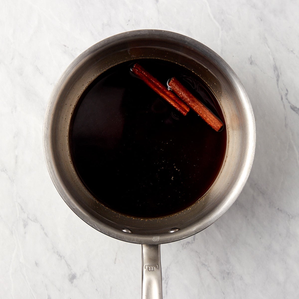 brown sugar simple syrup in a saucepan with cinnamon sticks.