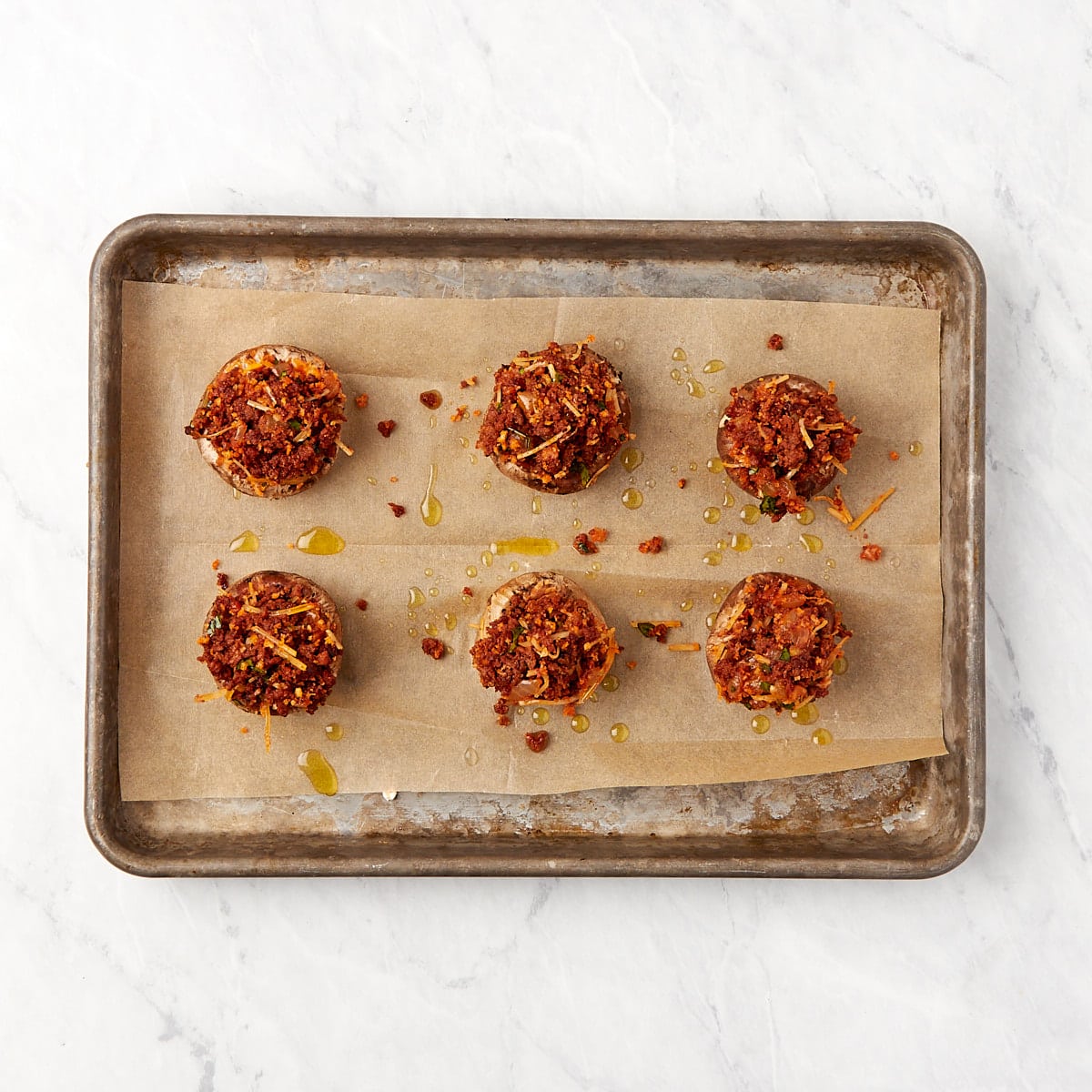 uncooked stuffed mushrooms on a baking sheet lined with parchment paper.