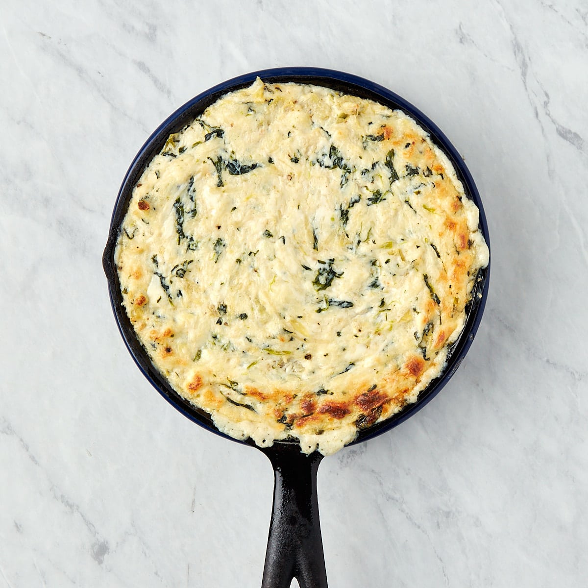 baked crab spinach artichoke dip in a skillet.